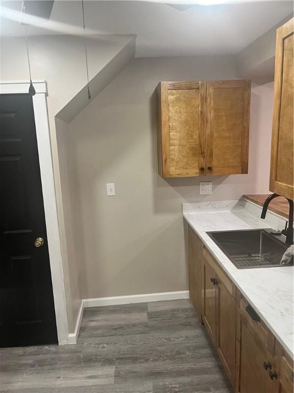 kitchen featuring a sink, baseboards, dark wood-style flooring, and brown cabinets