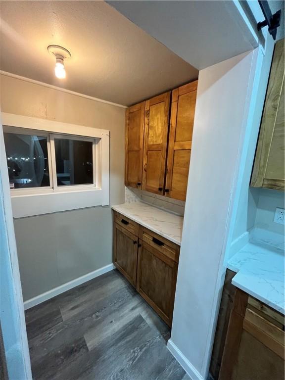 kitchen featuring baseboards, brown cabinetry, and dark wood-style floors