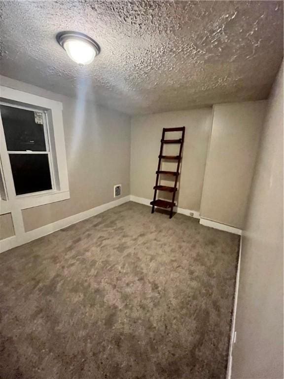 basement featuring a textured ceiling, carpet floors, and baseboards
