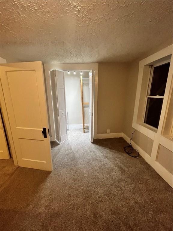 spare room featuring a textured ceiling and dark carpet