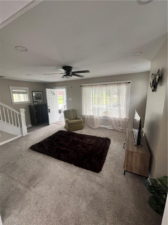 living area featuring carpet flooring, healthy amount of natural light, and ceiling fan