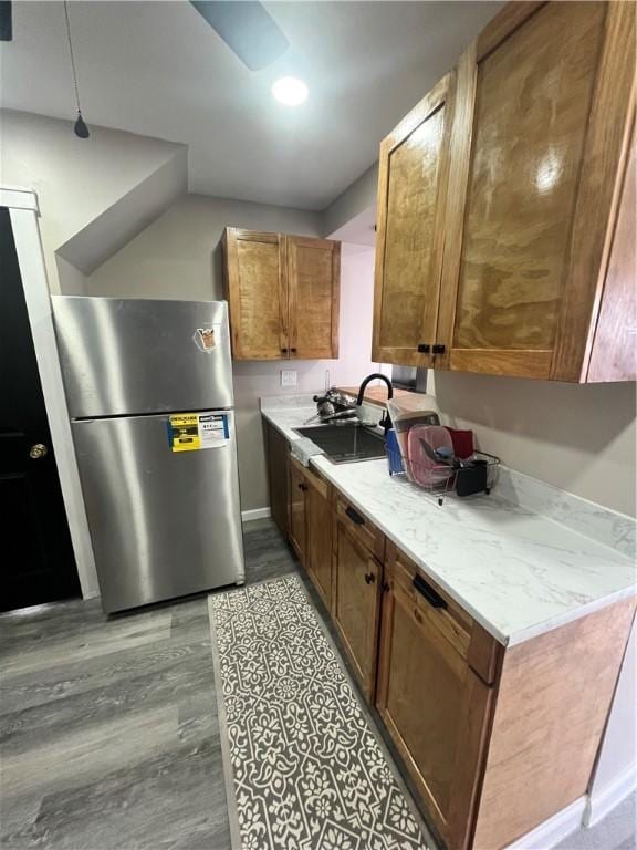 kitchen featuring freestanding refrigerator, a sink, light wood-style flooring, brown cabinets, and light countertops