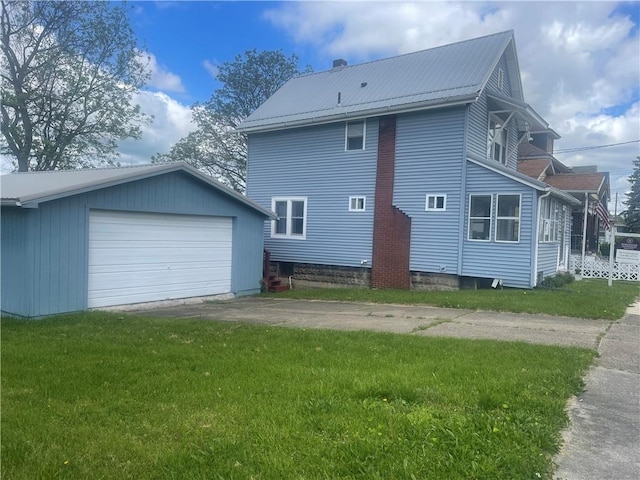rear view of property featuring an outbuilding, a garage, metal roof, and a yard