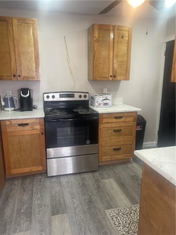 kitchen with electric range, dark wood-style flooring, light countertops, and brown cabinets