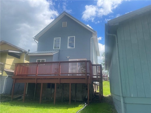 rear view of house featuring a wooden deck and a lawn