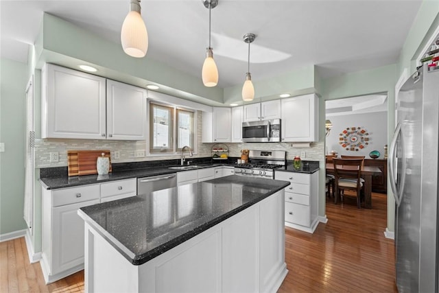 kitchen featuring a center island, sink, hanging light fixtures, appliances with stainless steel finishes, and white cabinets