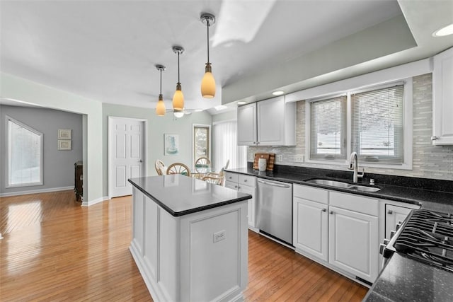 kitchen featuring a kitchen island, stainless steel dishwasher, sink, hanging light fixtures, and white cabinets