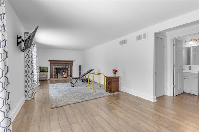 playroom with light wood-type flooring, sink, and a tiled fireplace