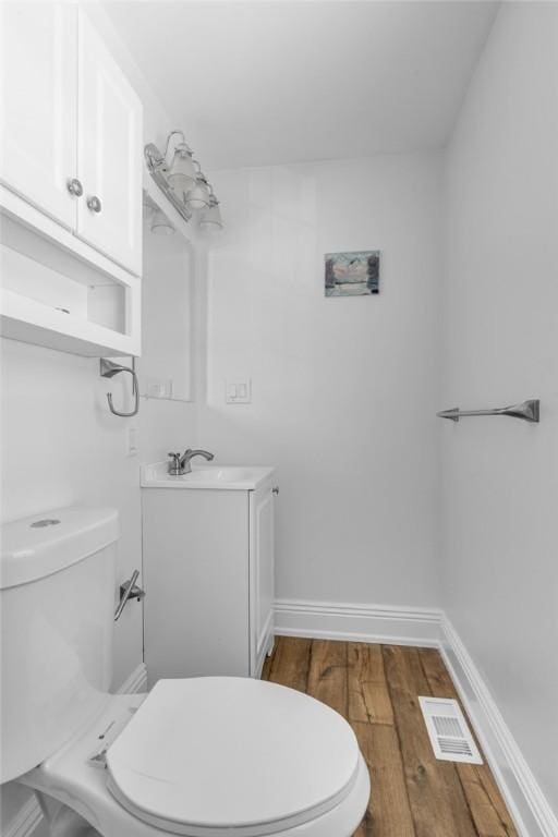 bathroom with toilet, hardwood / wood-style flooring, and vanity