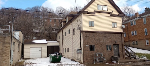 view of snow covered exterior with a garage and an outbuilding