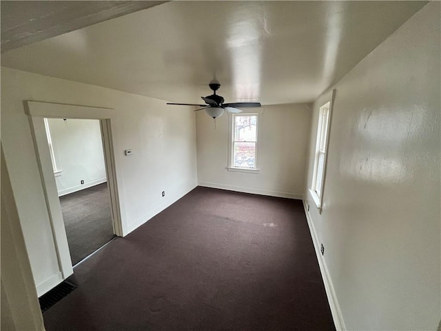 unfurnished room featuring ceiling fan and dark carpet