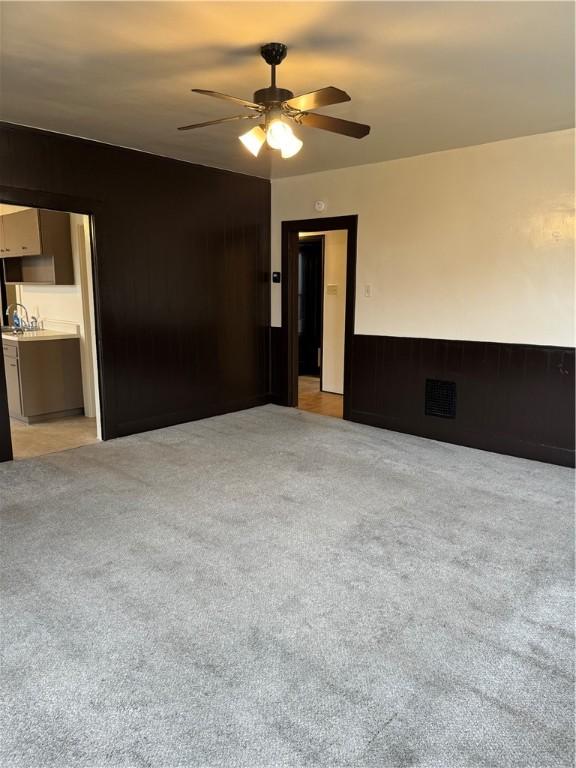 empty room with ceiling fan and light carpet