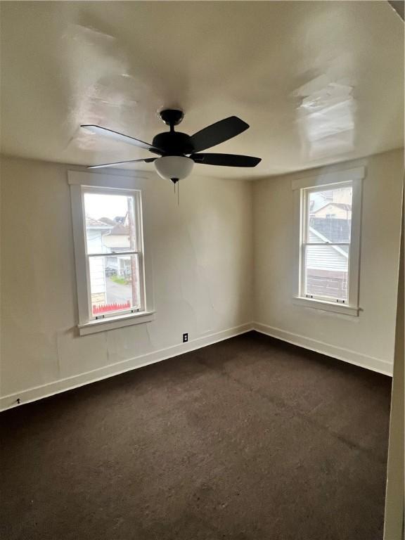 carpeted empty room featuring ceiling fan and plenty of natural light