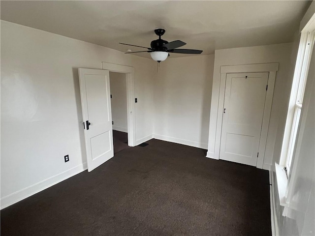 unfurnished bedroom with ceiling fan and dark carpet