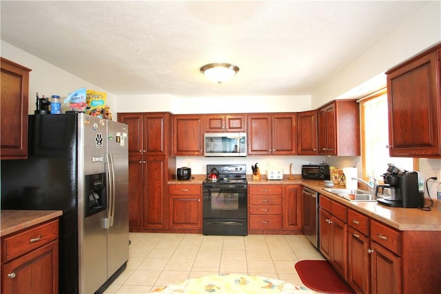 kitchen featuring appliances with stainless steel finishes, sink, and light tile patterned flooring