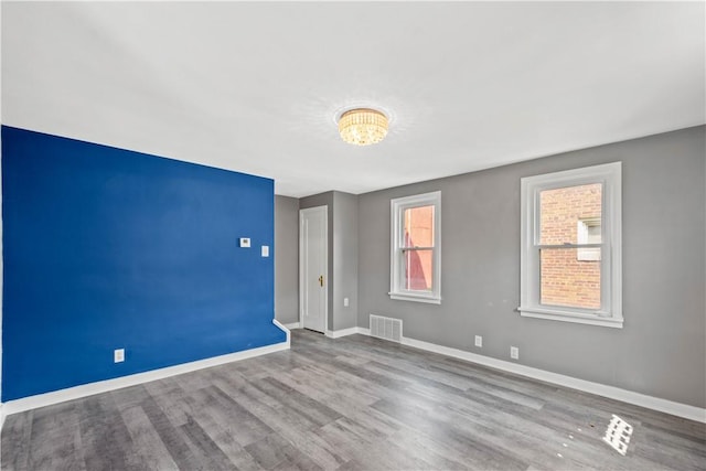 empty room with baseboards, visible vents, and wood finished floors