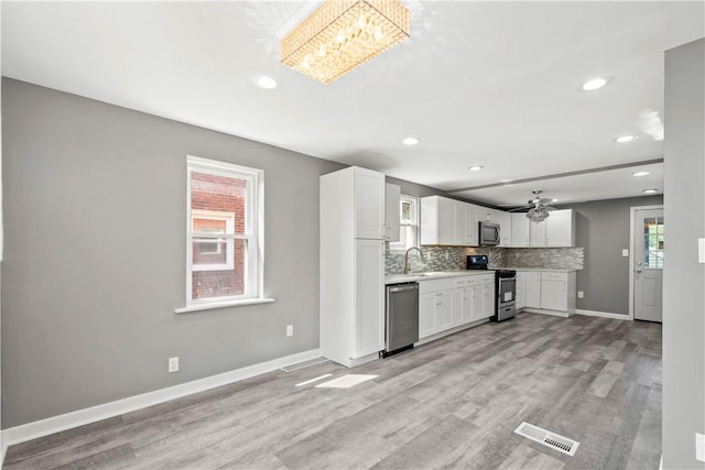 kitchen featuring stainless steel appliances, white cabinets, visible vents, and decorative backsplash