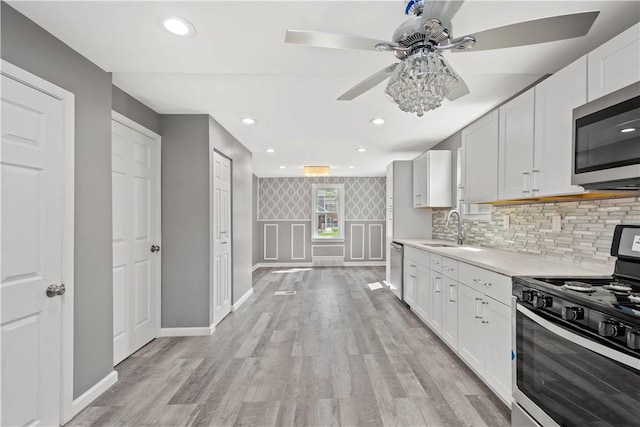 kitchen with light wood-type flooring, appliances with stainless steel finishes, light countertops, and a sink