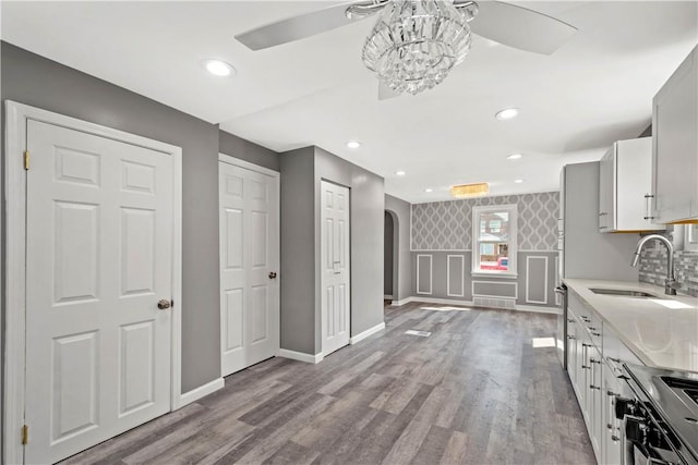 kitchen with arched walkways, light countertops, a sink, and wood finished floors