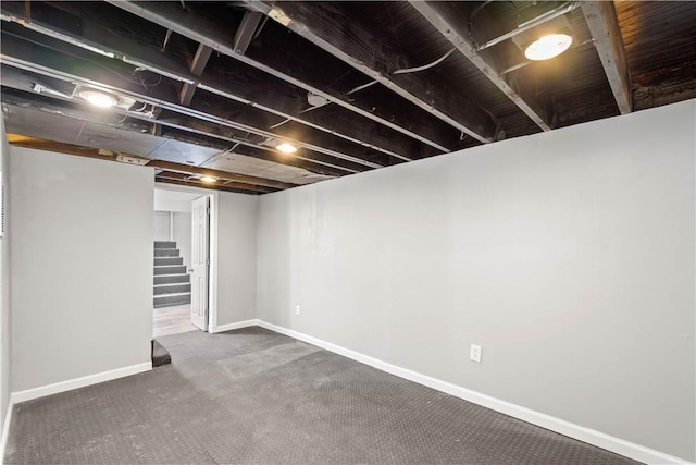 finished below grade area featuring carpet floors, baseboards, and stairway