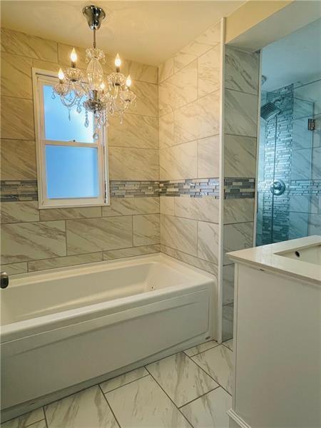 full bathroom featuring marble finish floor, a notable chandelier, and vanity