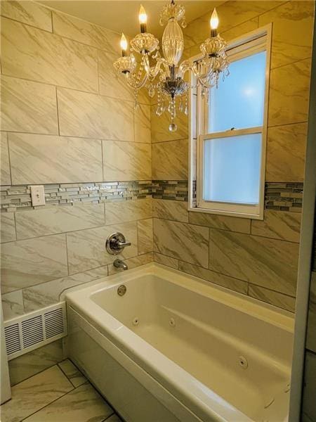 bathroom featuring visible vents, a jetted tub, marble finish floor, a chandelier, and tile walls