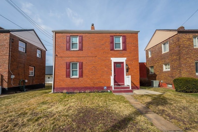 view of front of property featuring brick siding, a chimney, a front lawn, and central air condition unit