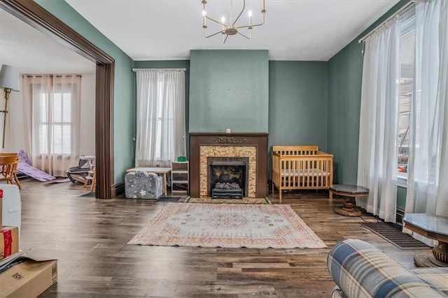 living area with dark wood-type flooring, a premium fireplace, and an inviting chandelier