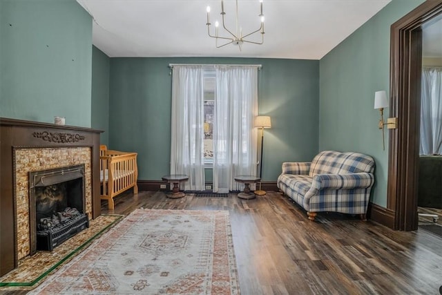 living area featuring a tiled fireplace, an inviting chandelier, and hardwood / wood-style flooring