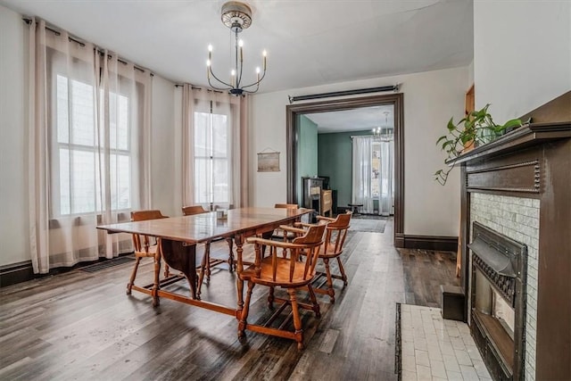 dining space featuring a brick fireplace, a chandelier, and dark hardwood / wood-style floors