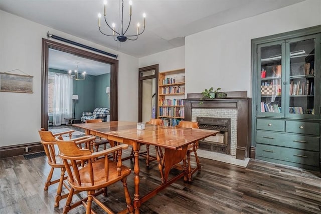 dining area with built in shelves, a fireplace, a notable chandelier, and dark hardwood / wood-style floors