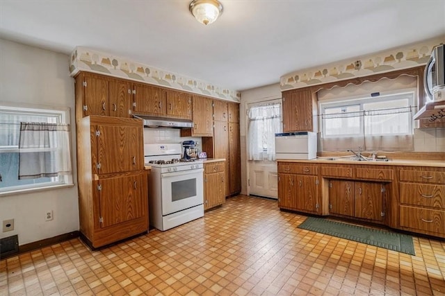 kitchen featuring sink, backsplash, and white range with gas cooktop