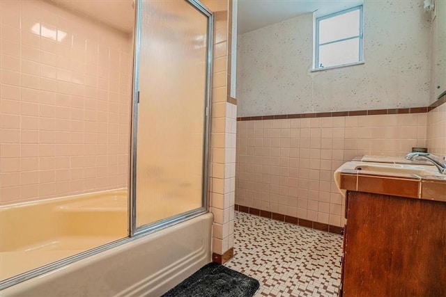 bathroom with vanity, tile walls, and shower / bath combination with glass door