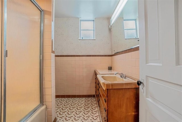 bathroom with tile walls, vanity, and shower / bath combination with glass door