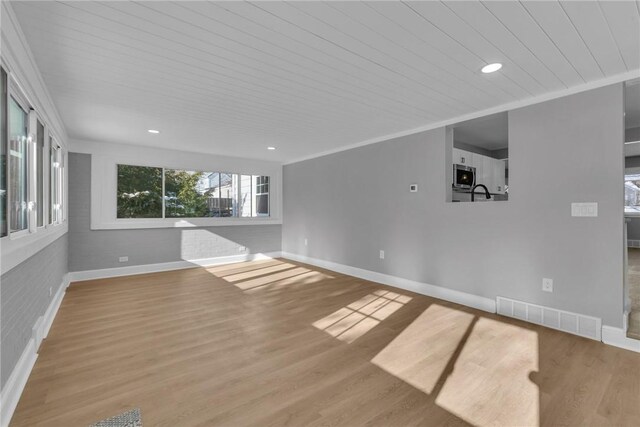 unfurnished living room with light wood-type flooring, wooden ceiling, and crown molding