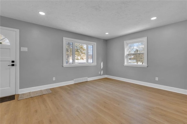 foyer entrance with light wood-type flooring and a textured ceiling