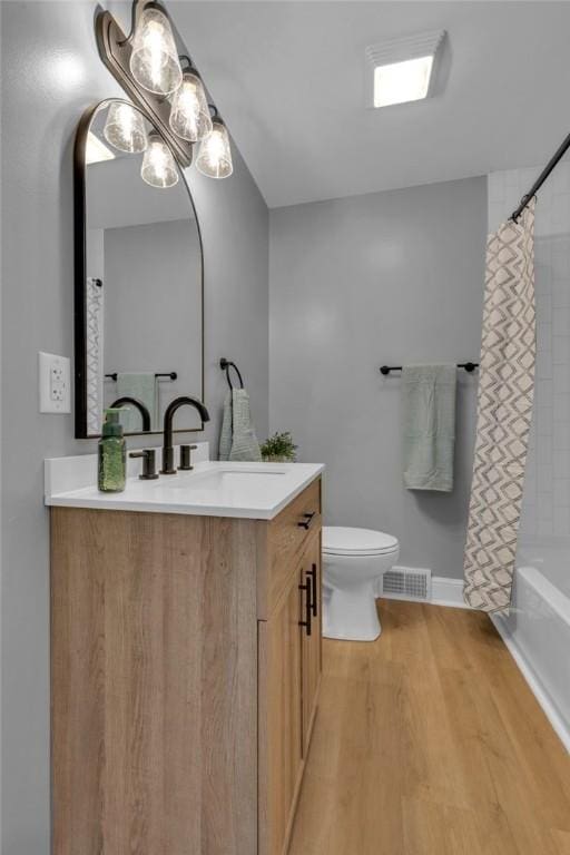 full bathroom featuring hardwood / wood-style floors, toilet, vanity, and shower / bath combo