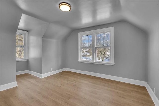 additional living space with vaulted ceiling, a wealth of natural light, and light hardwood / wood-style flooring