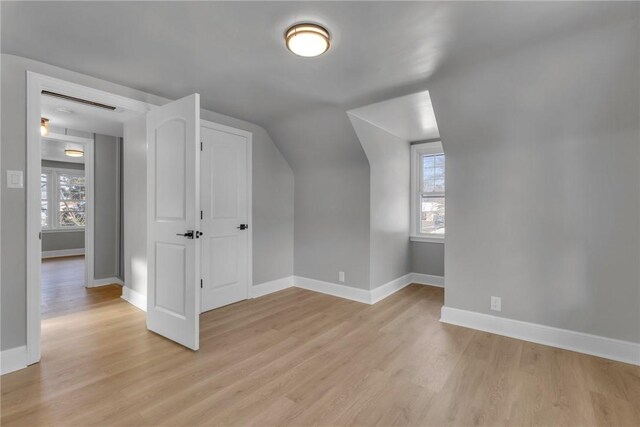 additional living space featuring vaulted ceiling and light wood-type flooring