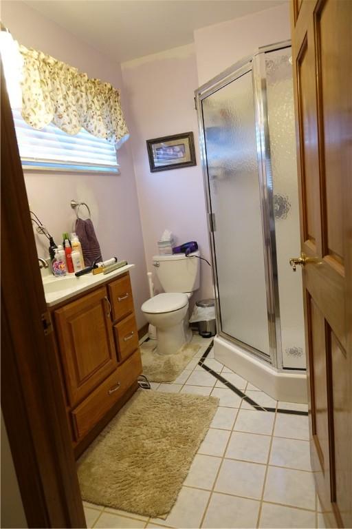 bathroom with walk in shower, tile patterned flooring, and toilet