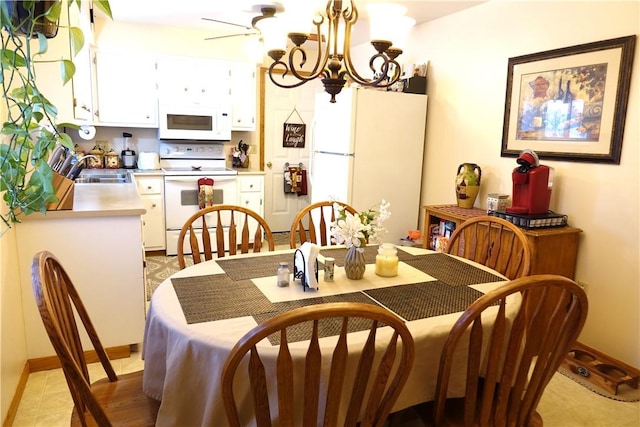 dining area featuring ceiling fan with notable chandelier and sink