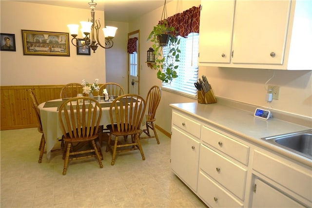 dining area featuring sink, wood walls, and a notable chandelier