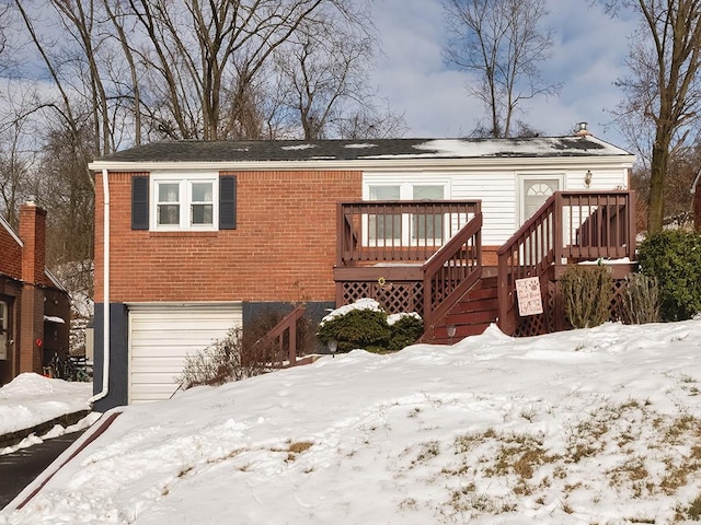 snow covered rear of property with a deck