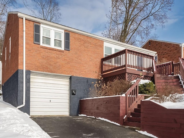 snow covered property featuring a garage and a wooden deck