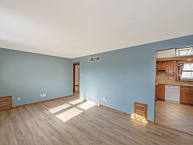 unfurnished living room featuring heating unit, light hardwood / wood-style flooring, and sink