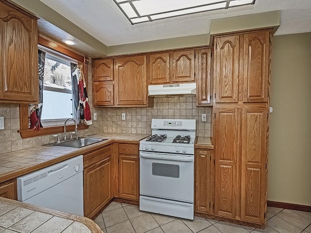 kitchen with white appliances, tasteful backsplash, sink, tile countertops, and light tile patterned flooring