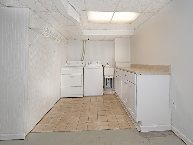 clothes washing area with sink, washing machine and dryer, light tile patterned flooring, and cabinets