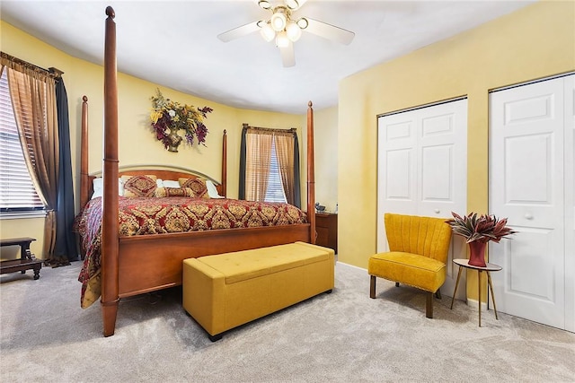 bedroom with ceiling fan, carpet, and multiple closets