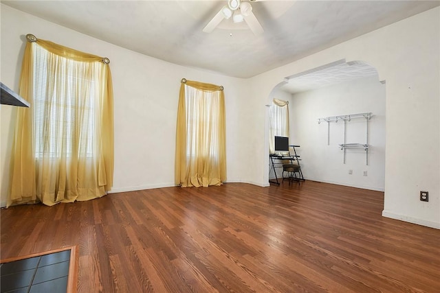 unfurnished living room with ceiling fan, dark hardwood / wood-style floors, and a wealth of natural light