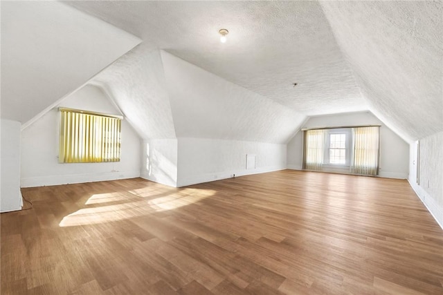 bonus room featuring vaulted ceiling, a textured ceiling, and hardwood / wood-style floors